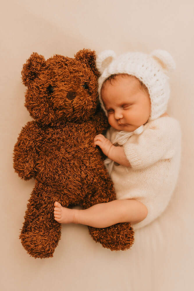 Teddy und Baby liegen sich in den Armen. (Franziska Kriening Fotografie)