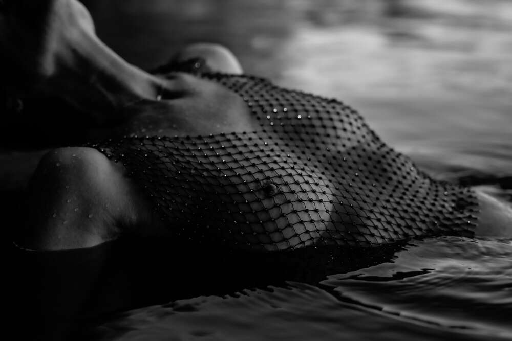 Frau liegt mit Netzpberteil im Wasser, sinnliche Fotografie. (www.susannewatrin.de)
