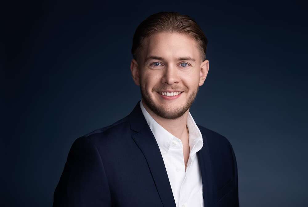 Studio-Porträt eines professionellen Immobilienmaklers in dunklem Anzug und weißem Hemd (Headshot Master)
