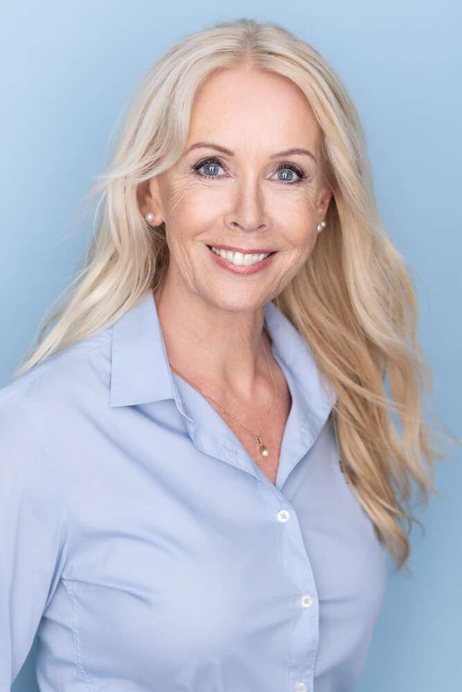 Studio-Porträt einer attraktiven, lächelnden Frau mit langen blonden Haaren. (Headshot Master)