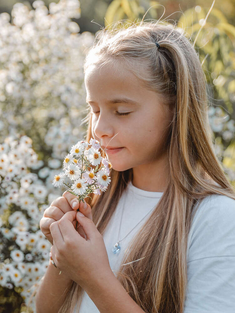 Mädchen riecht an Blumenstrauß  (Axel Jahnke | Fotografie)