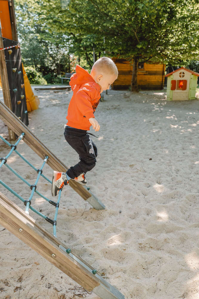 Junge springt vom Klettergerüst am Fototag im Kindergarten  (Axel Jahnke | Fotografie)