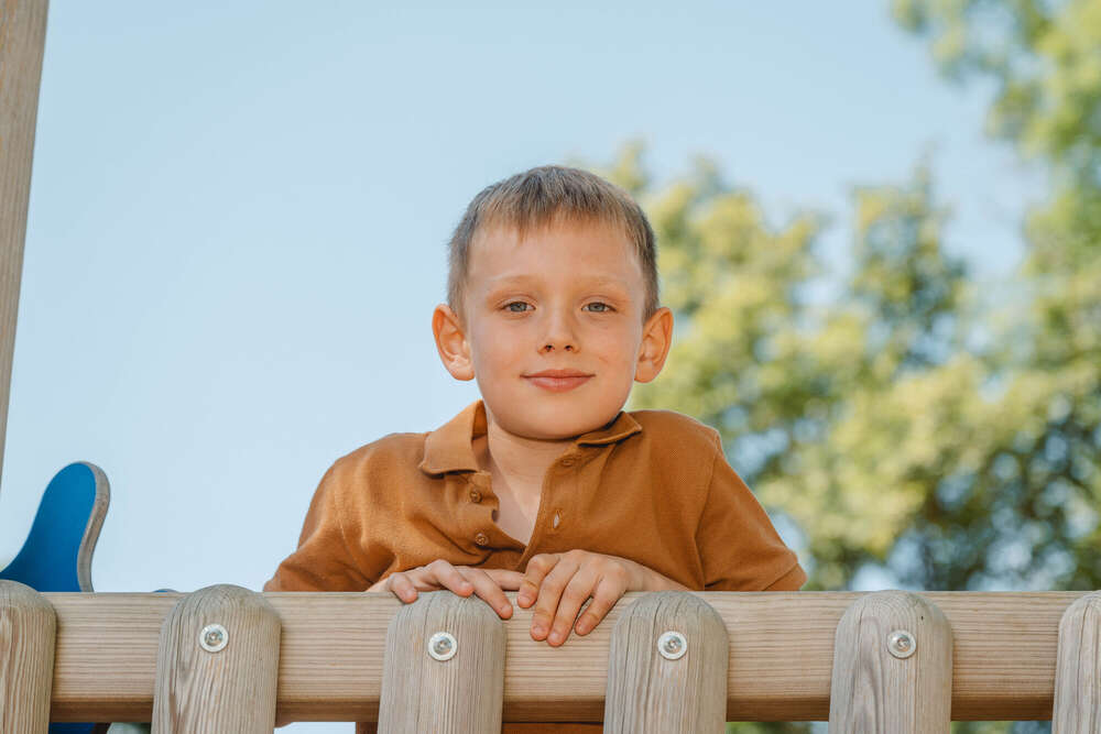 Portait eines Jungen, schaut vom Klettergerüst herunter.  (Axel Jahnke | Fotografie)