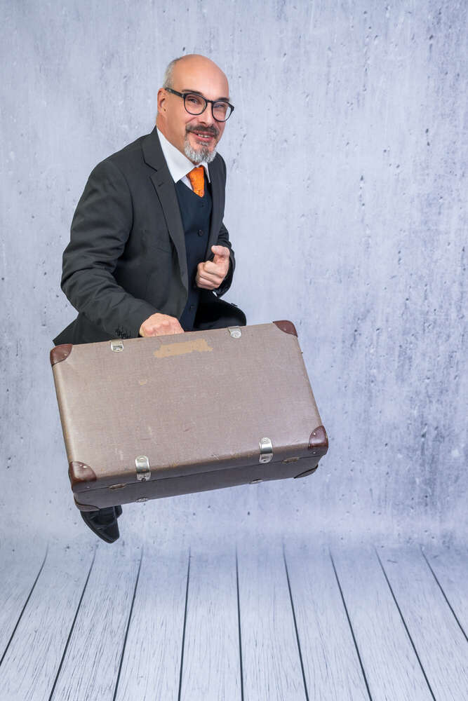 Mann im Anzug springt mit vintage Koffer hoch (Axel Jahnke | Fotografie)