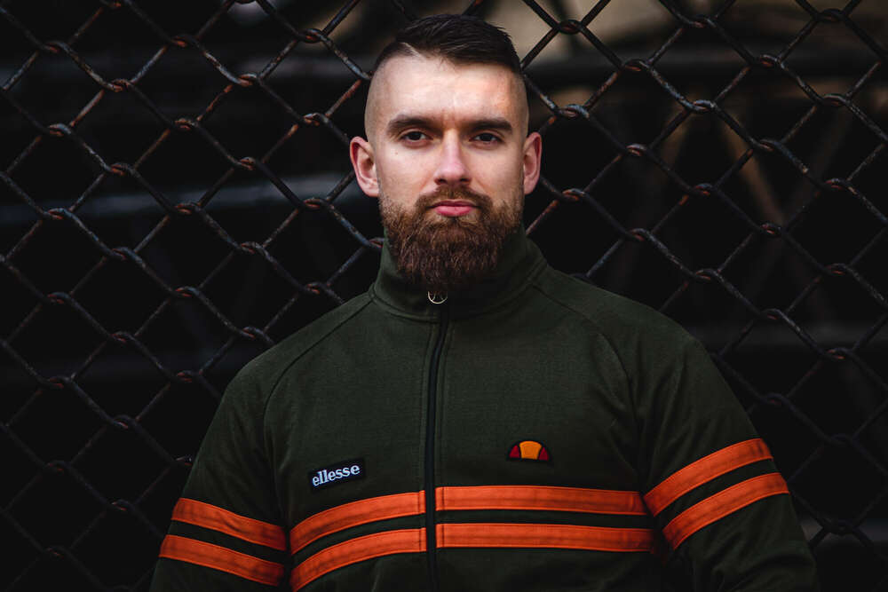 Ein m&auml;nnliches Modell vor einem Maschendrahtzaun (Leonard Maleika)