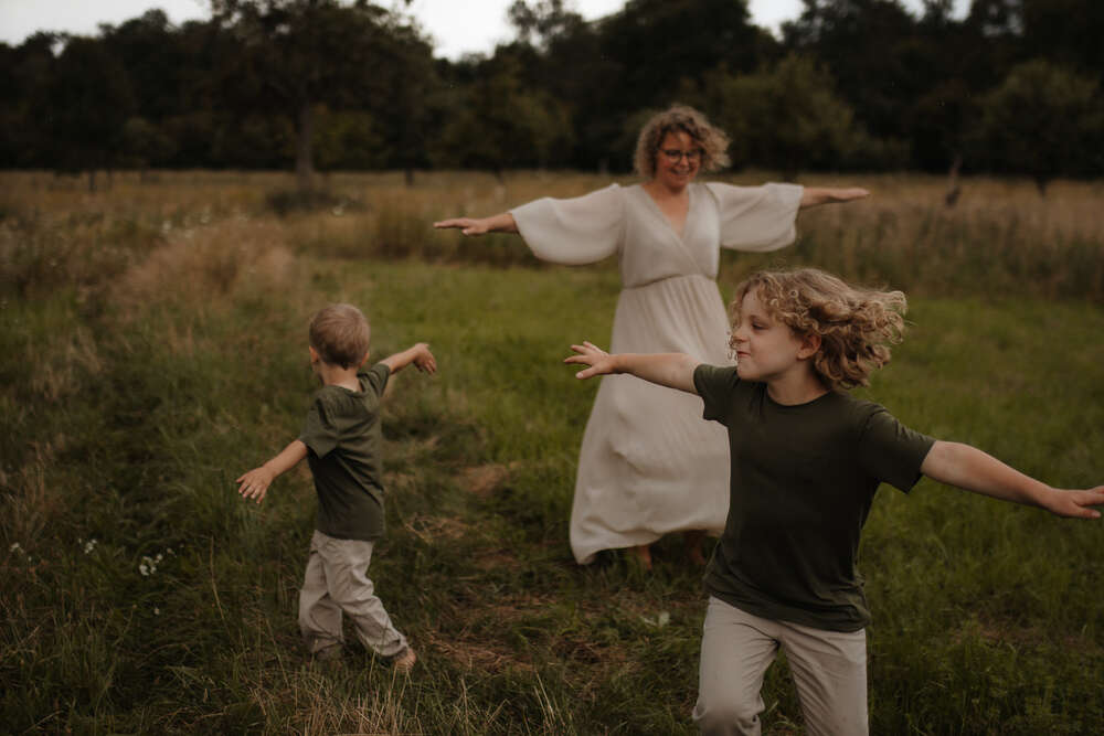 Mama dreht sich mit Kindern auf einer Wiese (Barbara Kern Familienfotografie)