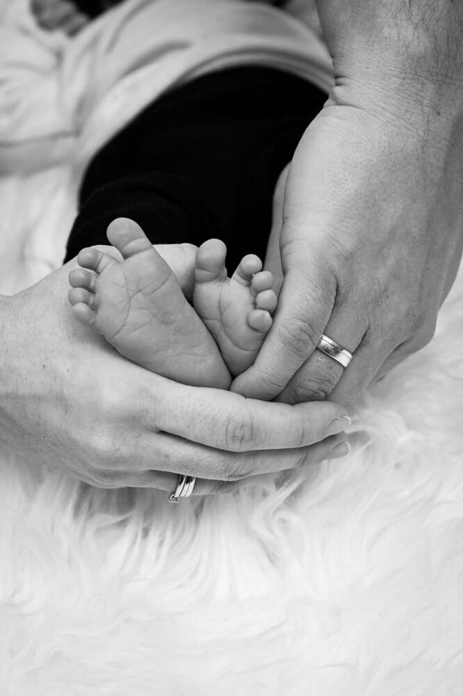 Symbol für Liebe – Herz aus Elternhänden um Babyfüße in Schwarz-Weiß (FOKUSNAH)